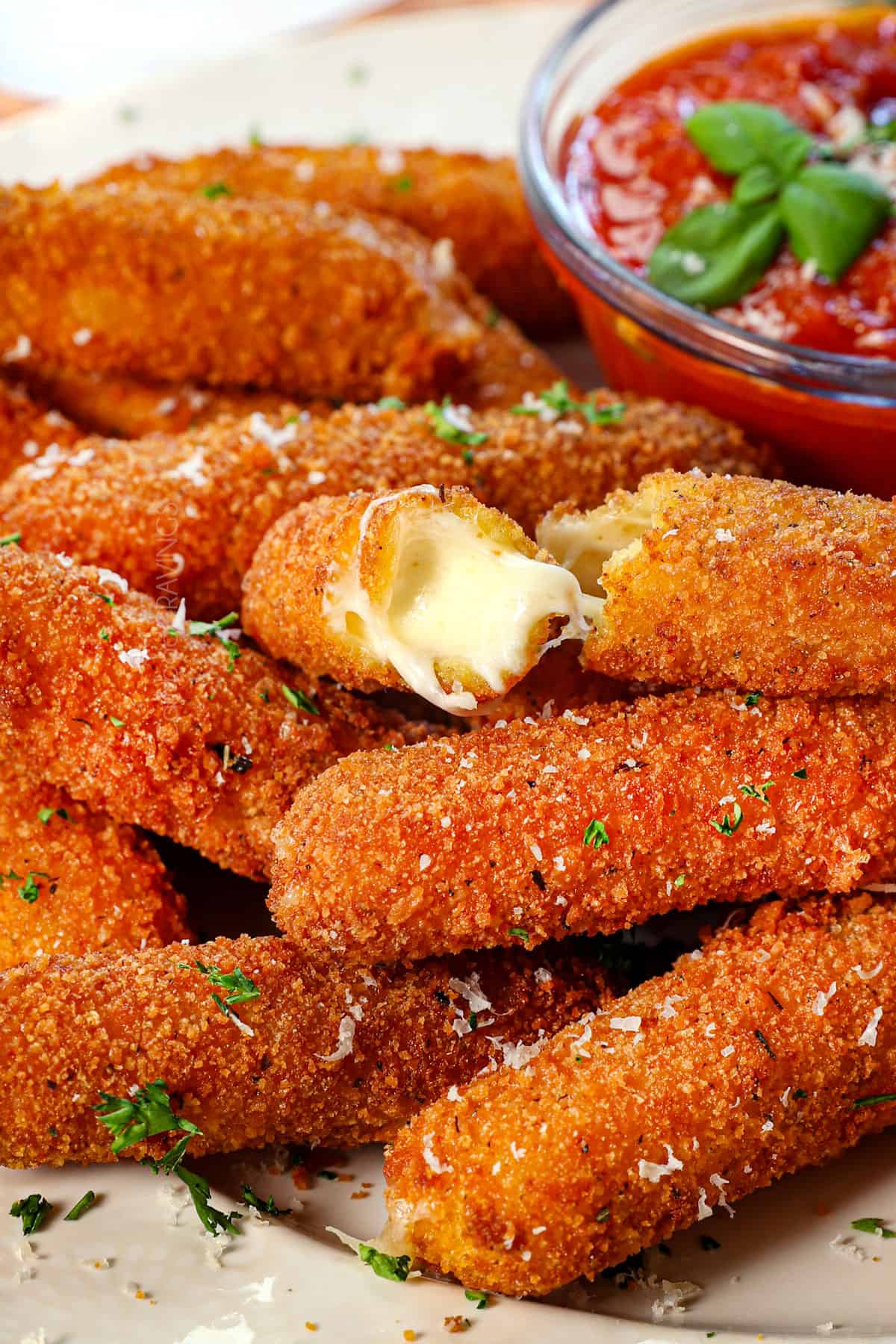 up close of homemade mozzarella sticks with a cheese stick pulled apart showing the cheesiness