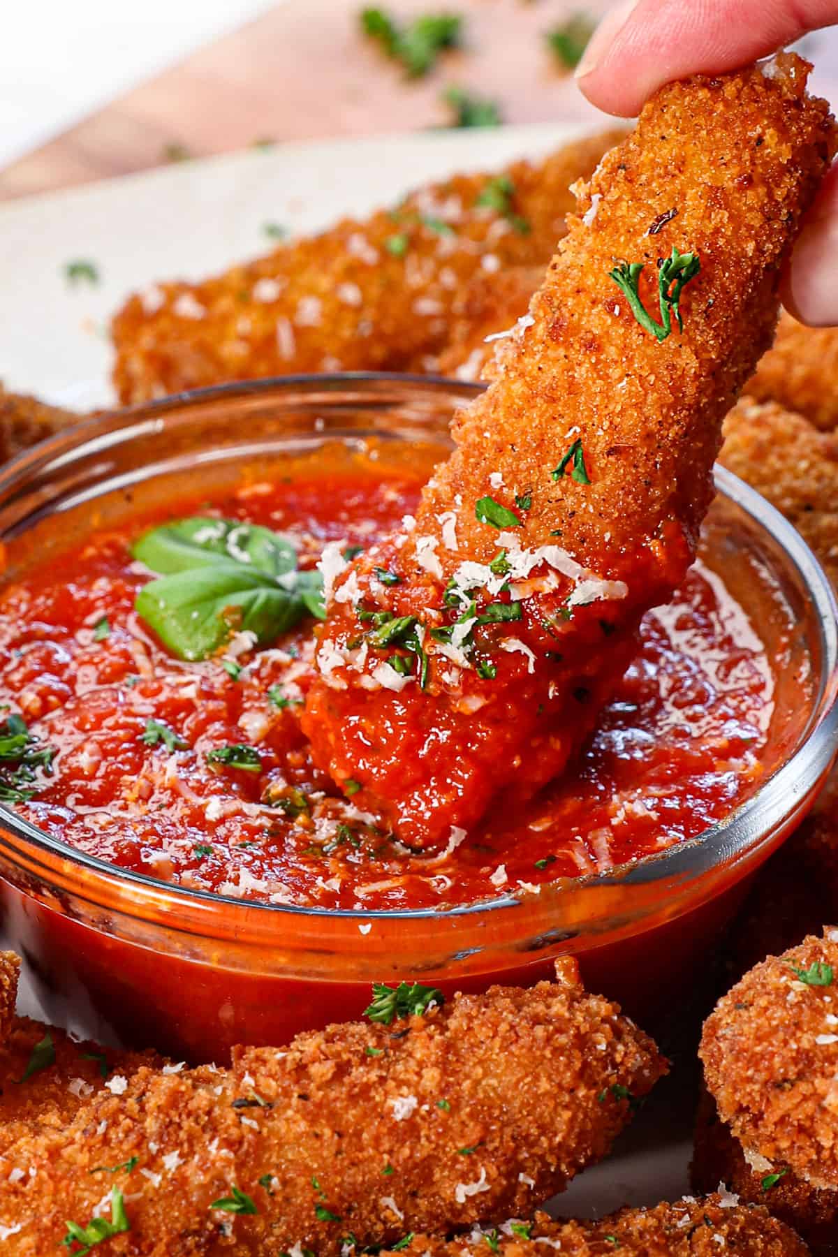 showing how to serve mozzarella sticks by dipping into marinara sauce