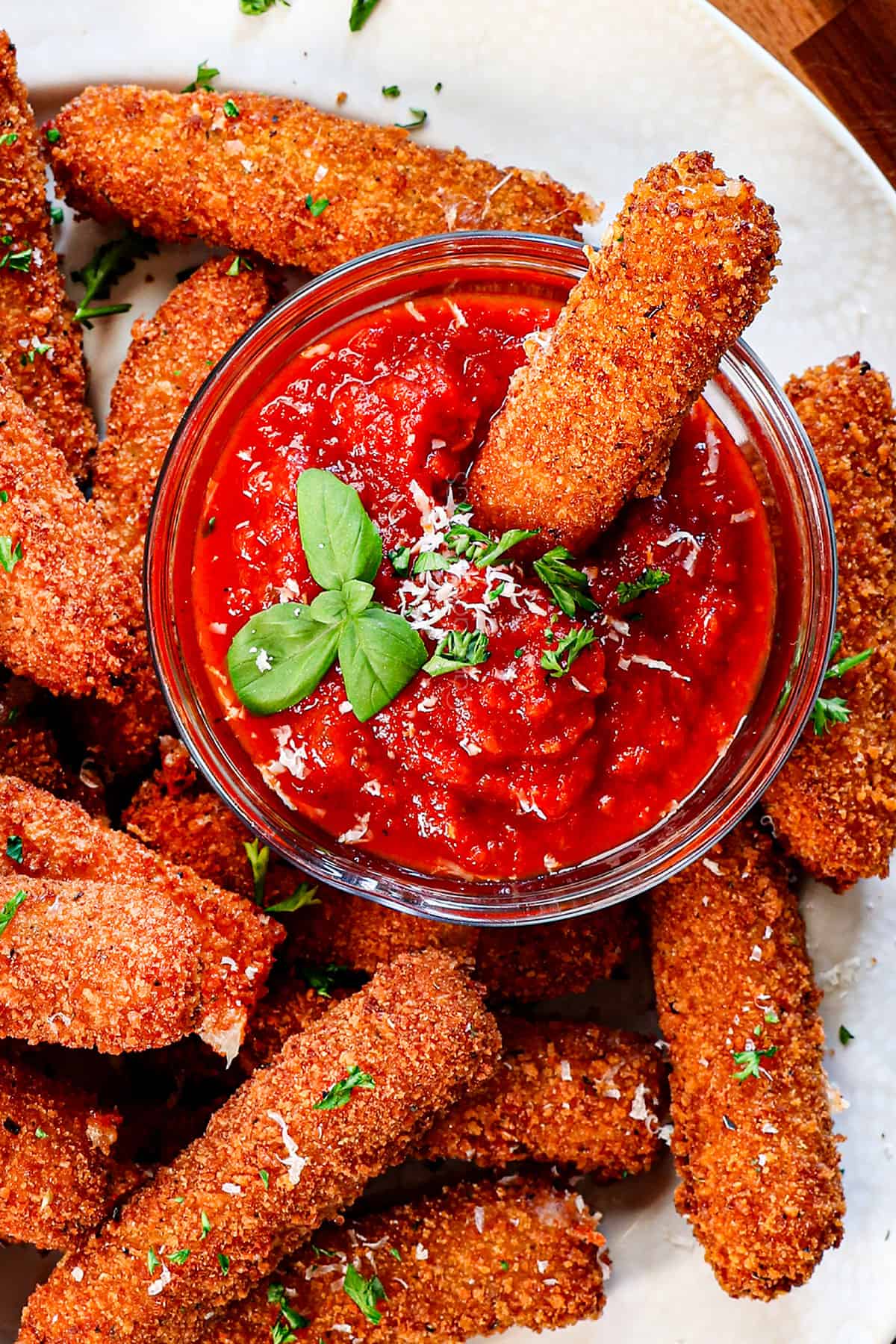 top view of mozzarella sticks recipe with a cheese stick dipped in marinara