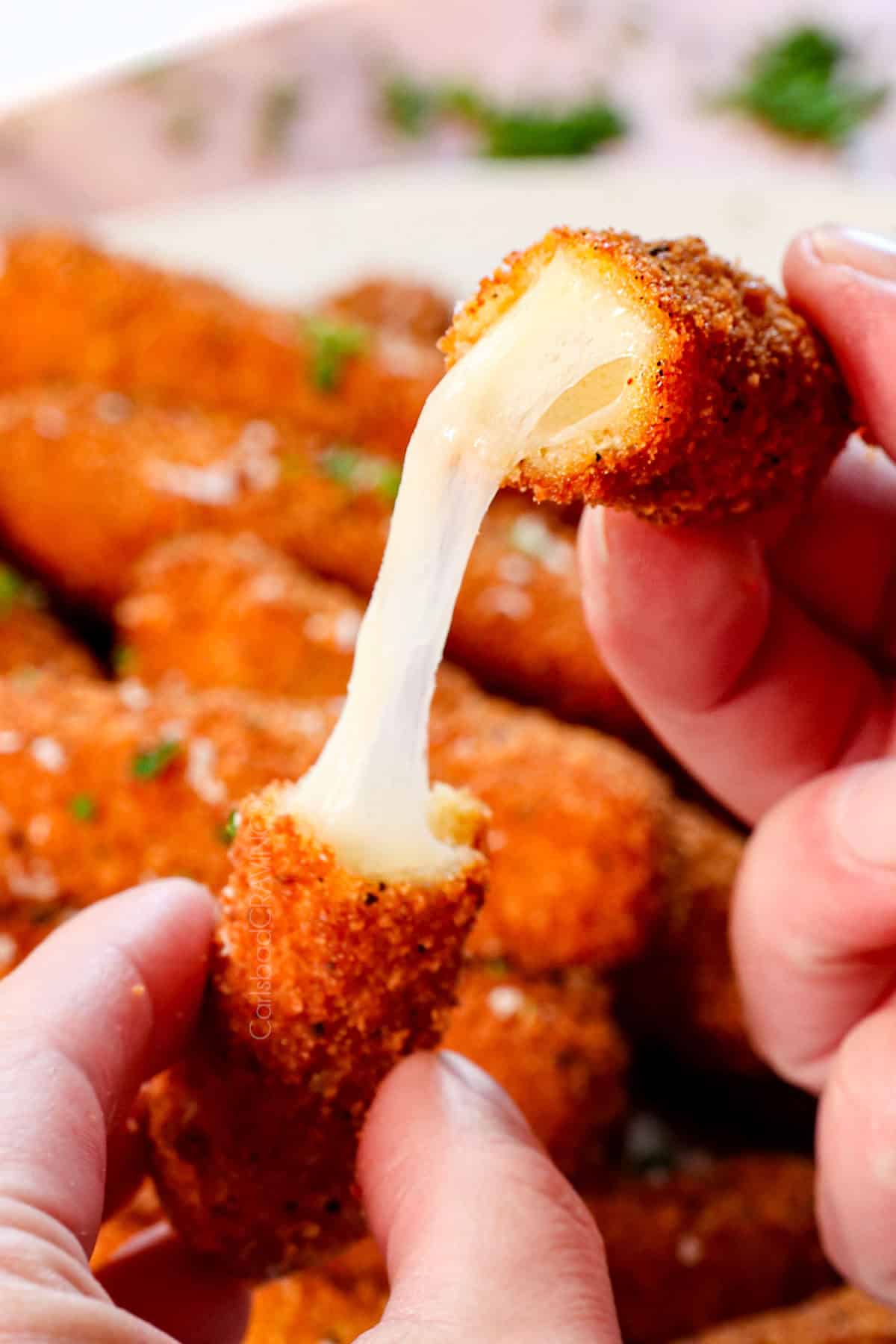 up close of pulling mozzarella stick recipe apart showing the melty cheese