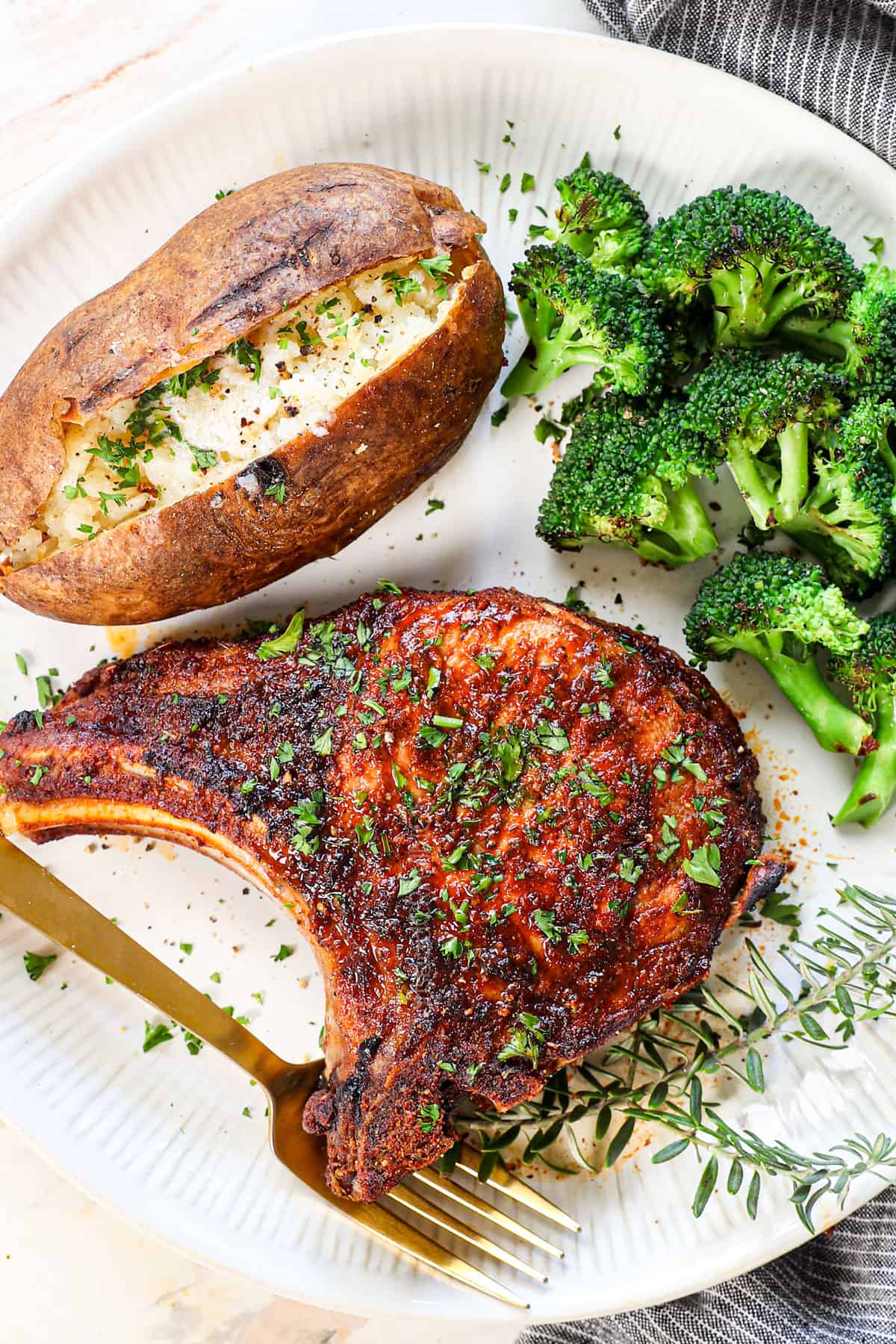 top view of pork chops in the air fryer served on a plate with broccoli and baked potato 