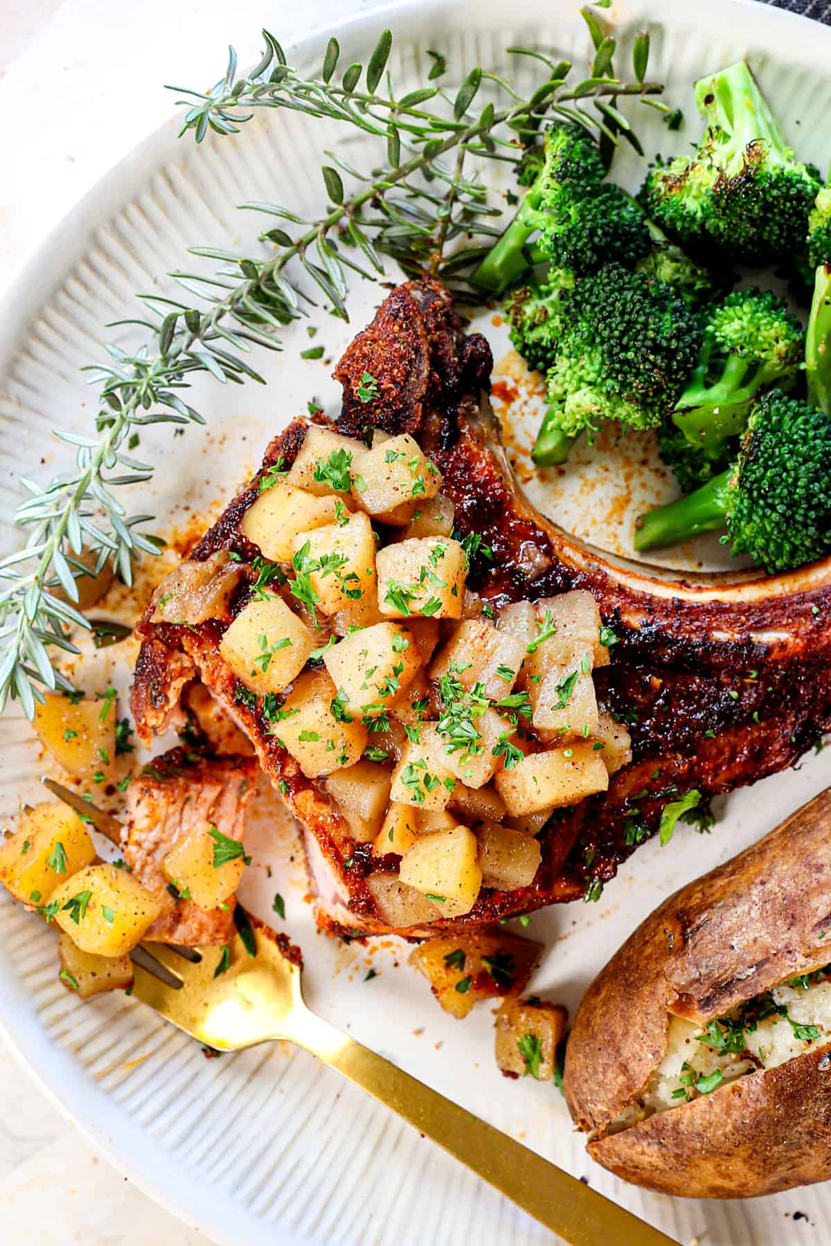 top view of pork chops in the air fryer served on a plate with broccoli and baked potato