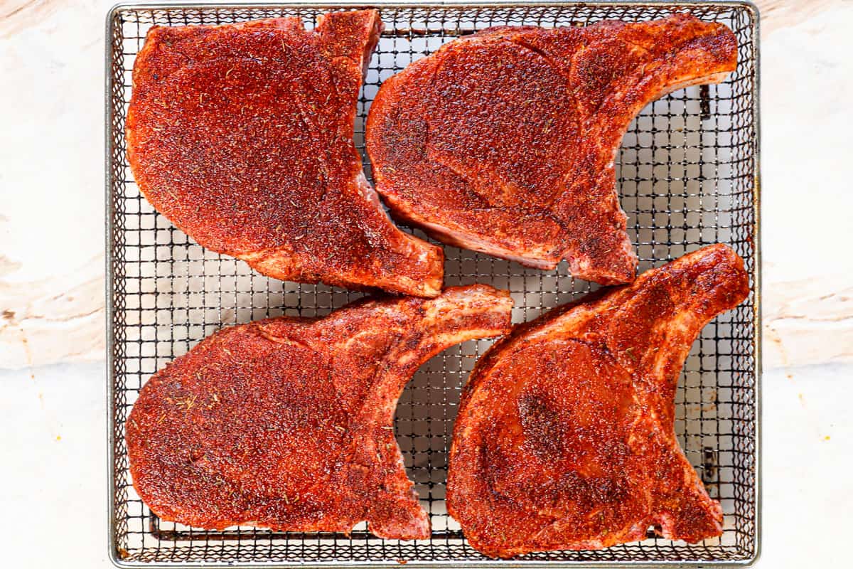 showing how to air fry pork chops by lining them in the air fryer basket and air frying for 12-16 minutes