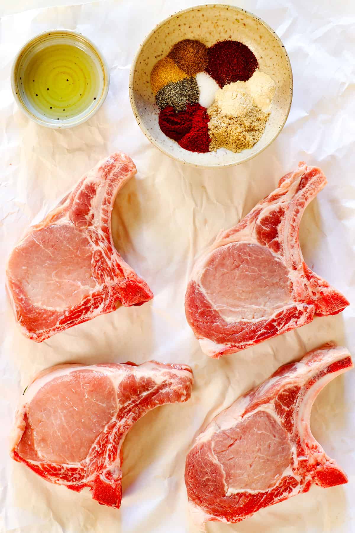 showing ingredients for pork chops in air fryer: 4 center-cut pork chops, spices and olive oil 