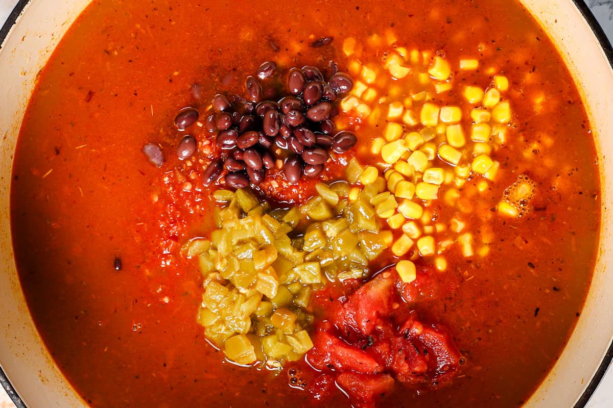showing how to make chicken taco soup recipe by returning the chicken to the pot, followed by the chicken broth, black beans, corn, diced tomatoes, green chiles, and bouillon.  
