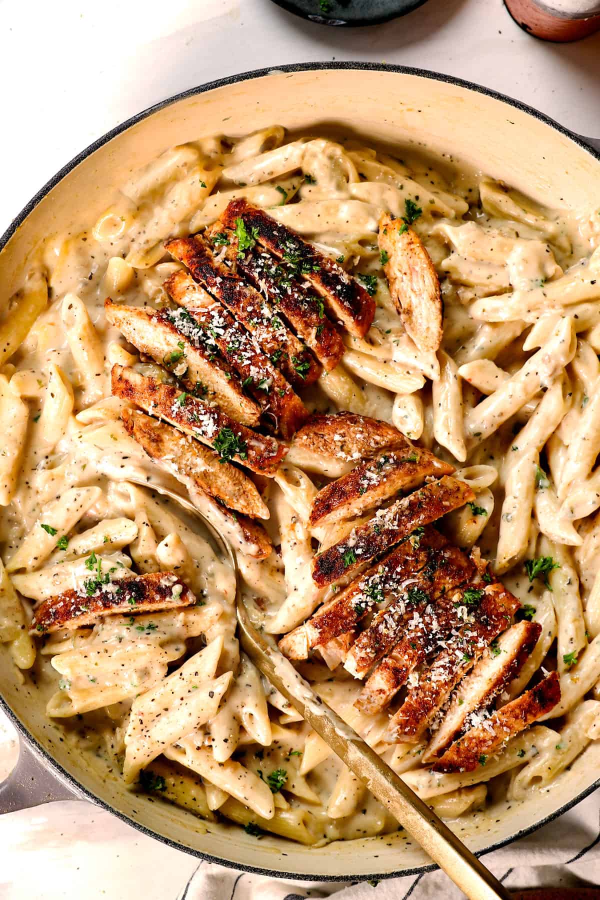 showing how to make garlic parmesan chicken pasta by laying the sliced chicken on the pasta