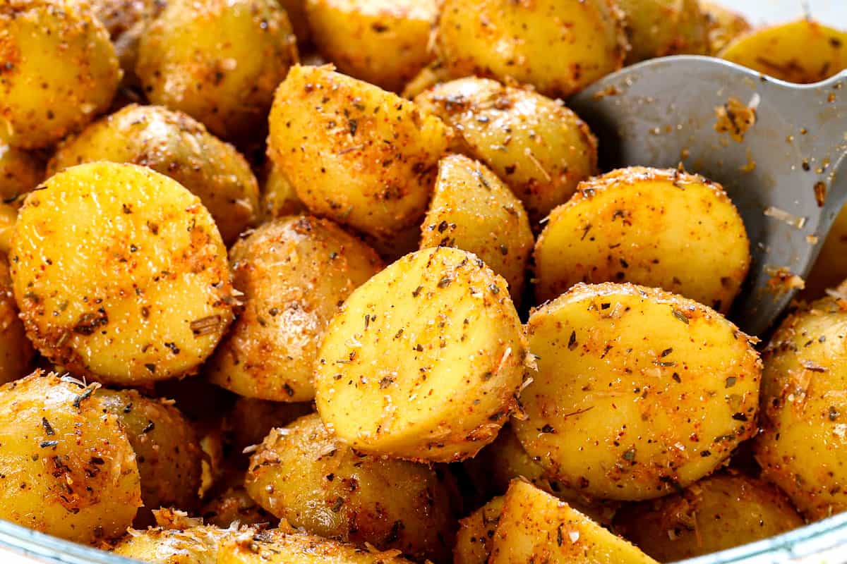 showing how to make roasted potatoes by stirring potatoes with olive oil, spices, and Parmesan cheese 