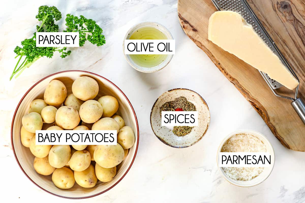 top view showing ingredients for roasted potatoes: baby potatoes, olive oil, spices, Parmesan and parsley 