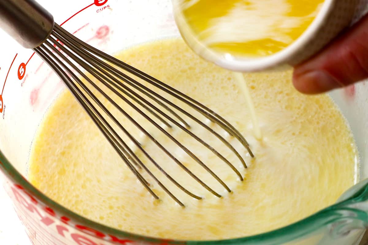 showing how to make fluffy pancakes by whisking in the melted butter while whisking constantly. 