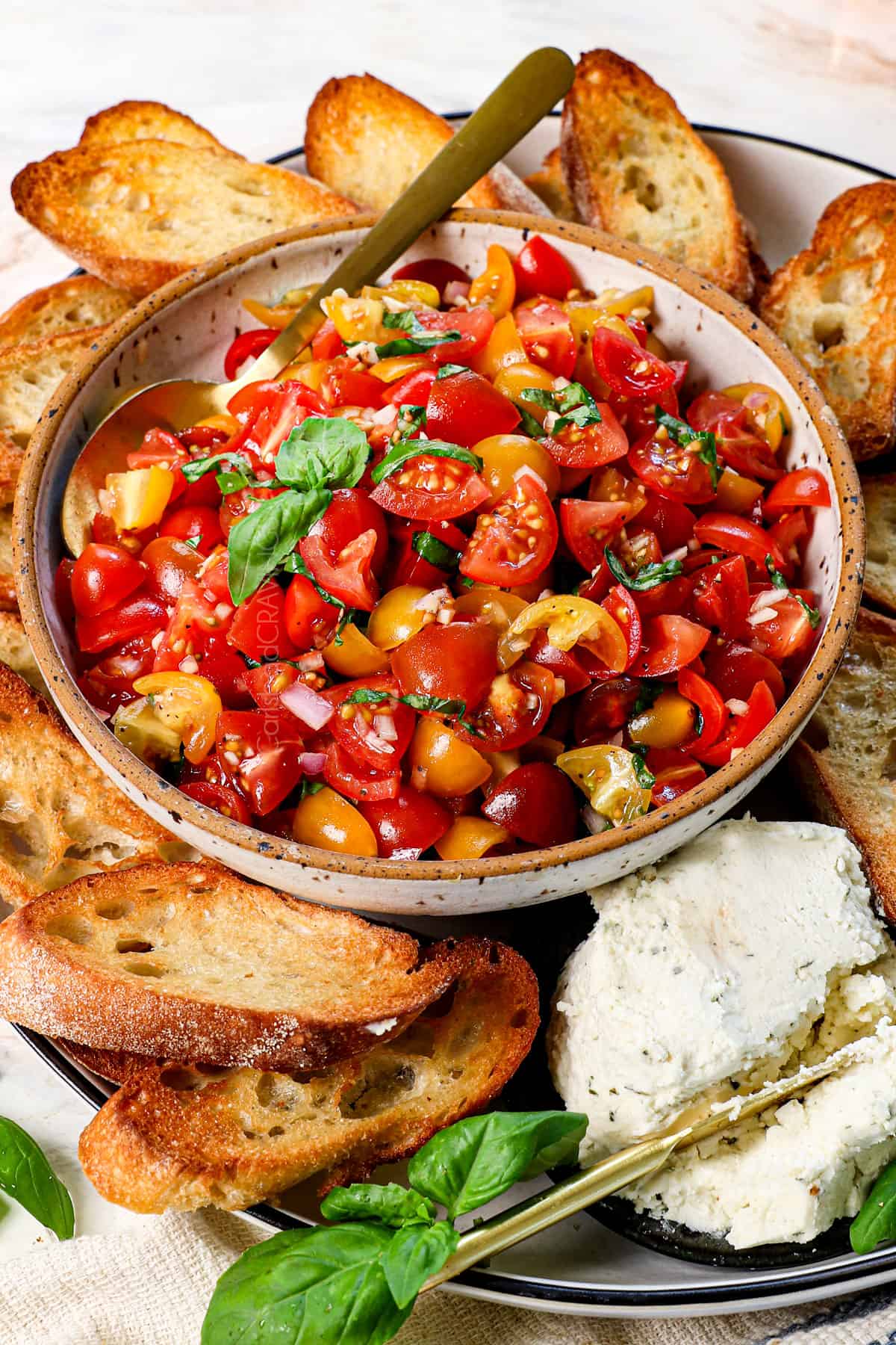 tomato bruschetta being served in a bowl, surrounded by toasts