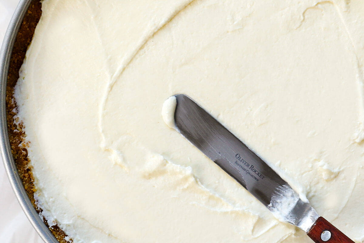showing how to make no bake cheesecake by smoothing the filling into the crust and chilling