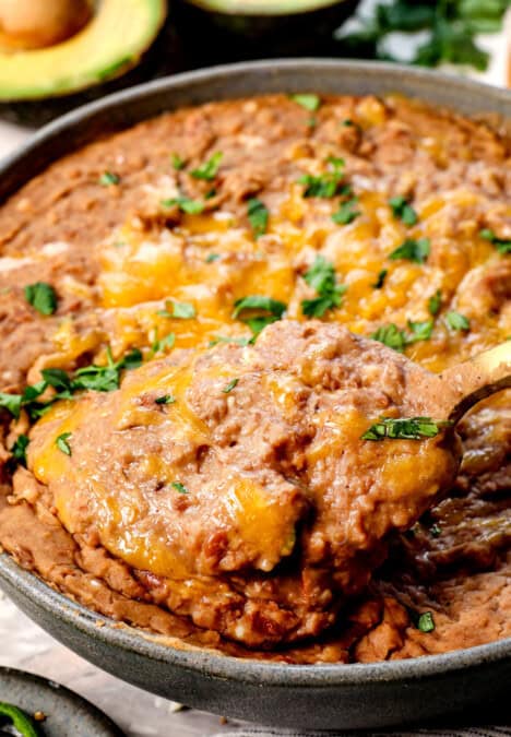 scooping up refried pinto beans with a spoon showing how creamy they are