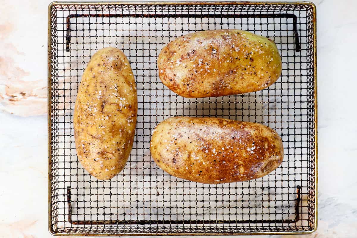 showing how to make baked potatoes in air fryer by placing the potatoes evenly in the air fryer basket without touching to air fry