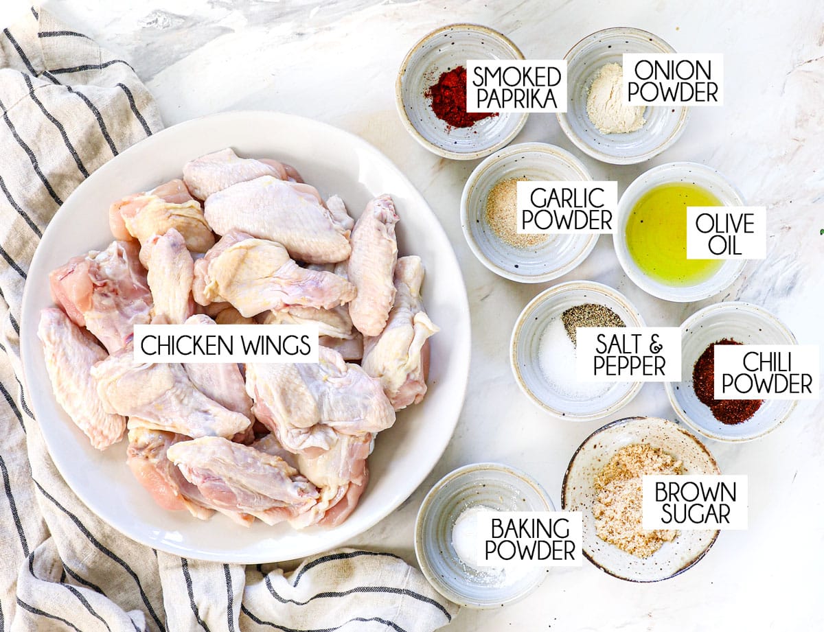 top view of air fryer chicken wings ingredients: chicken wings, olive oil, baking powder, onion powder, garlic powder, smoked paprika, salt and pepper