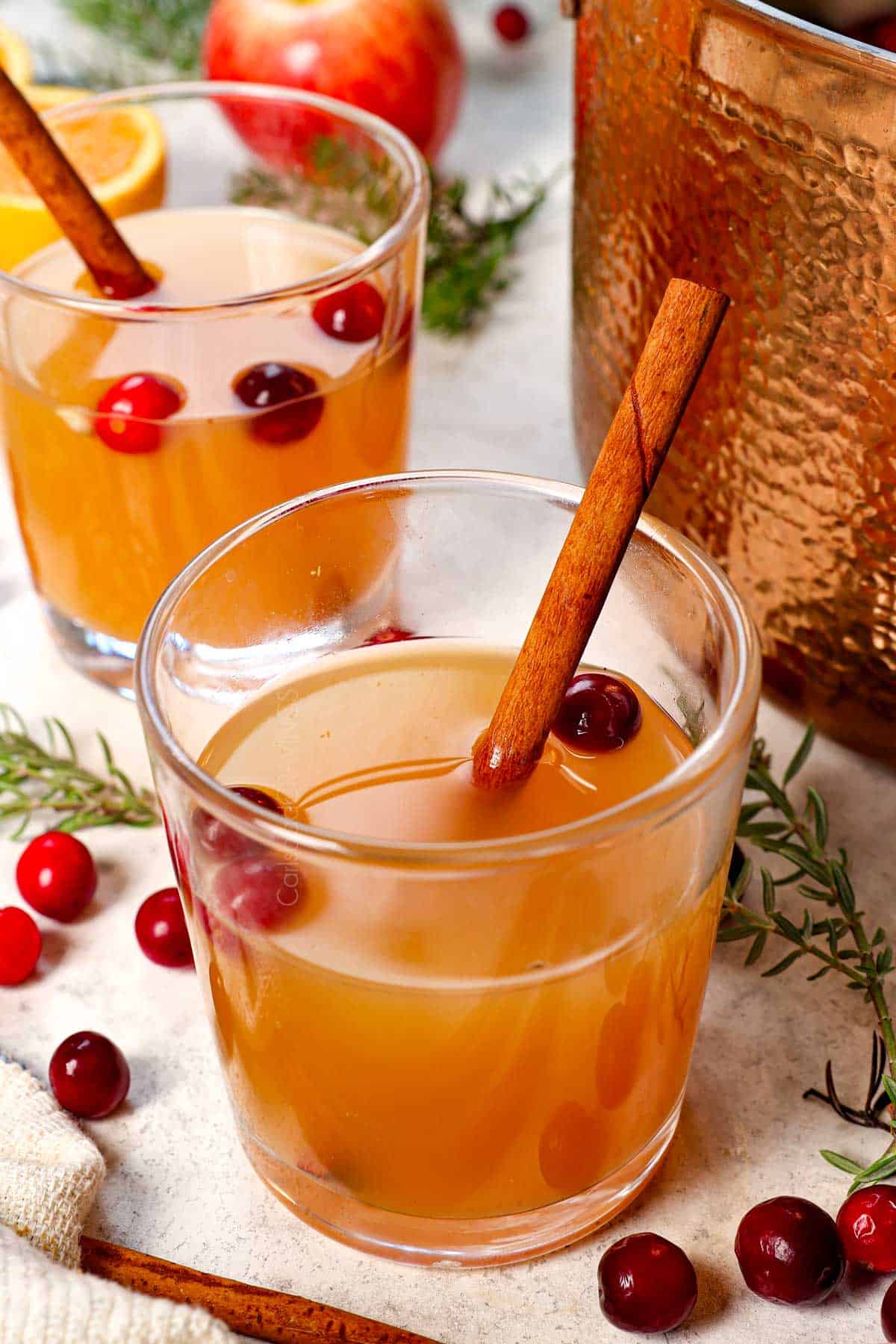 wassail recipe being served in glasses with a stick of cinnamon