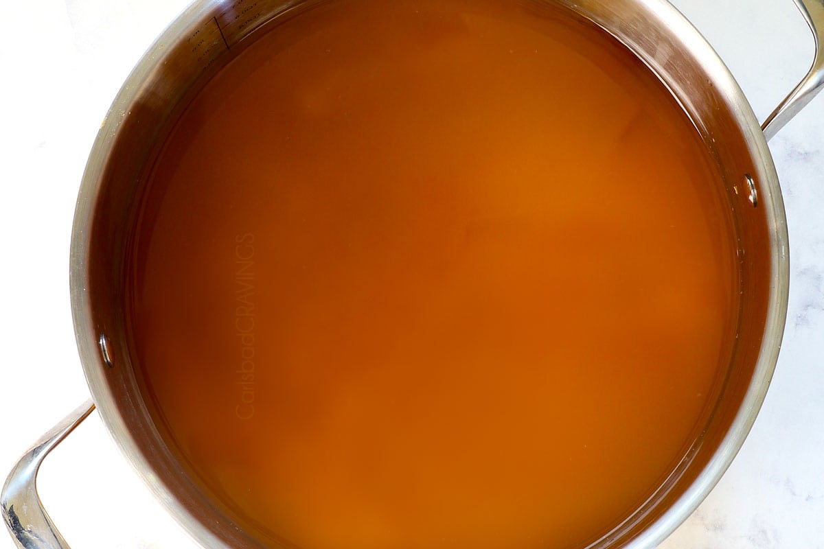 showing how to make wassail by adding the apple cider, orange juice concentrate, lemonade concentrate, sugar, water to a large pot