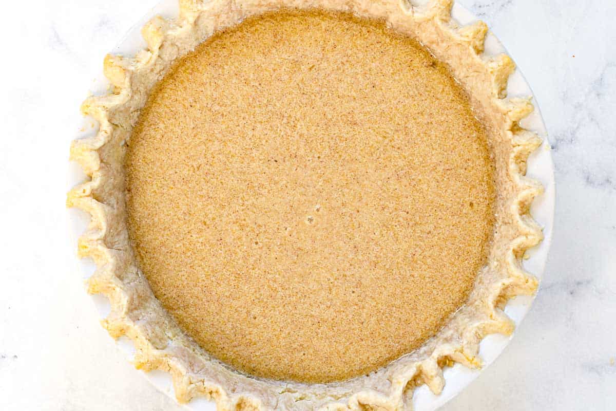 showing how to make chess pie by pouring the custard into the par-baked pie crust and baking until set