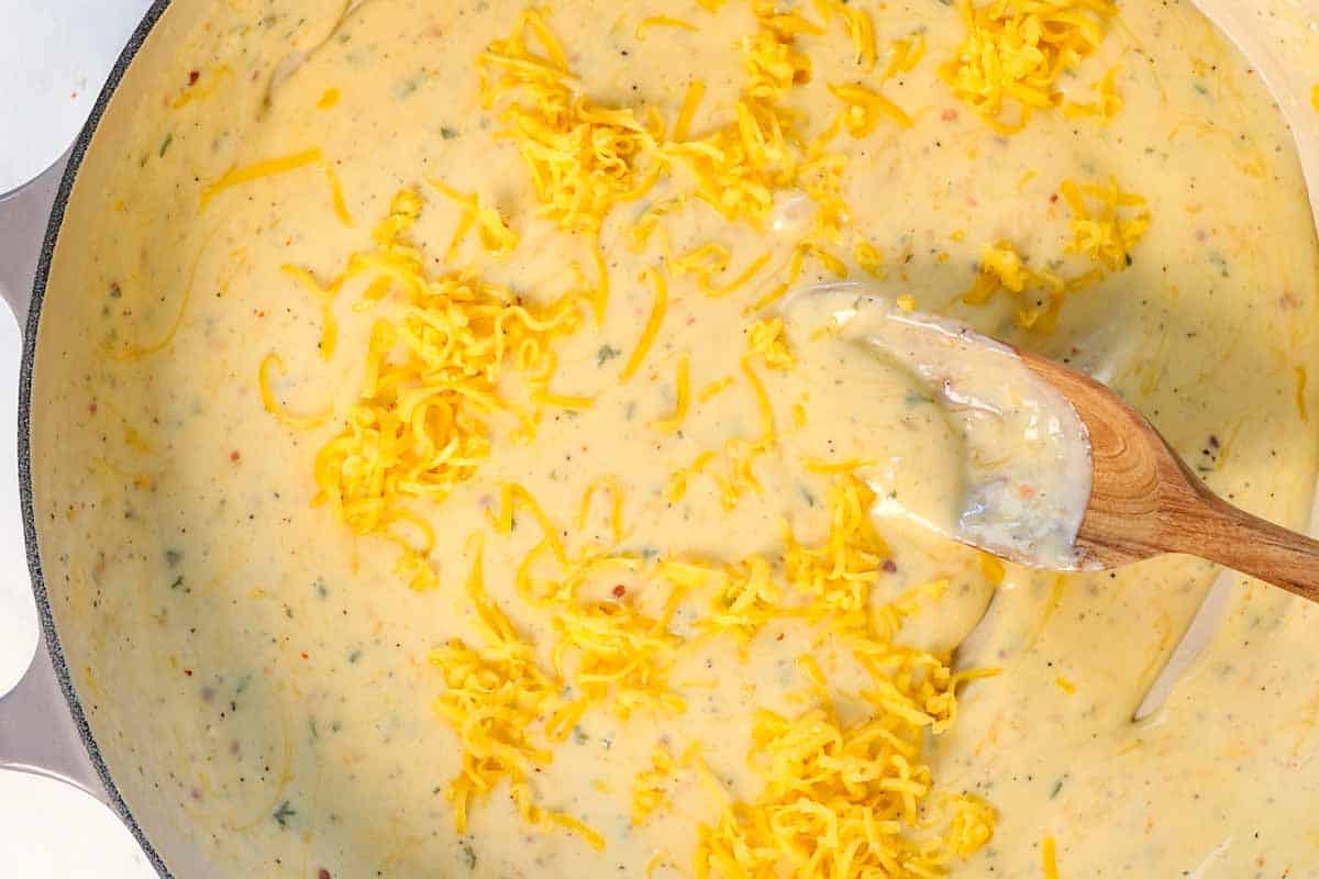 showing how to make Mac and Cheese Bites by stirring in cheeses a handful at a time until melted