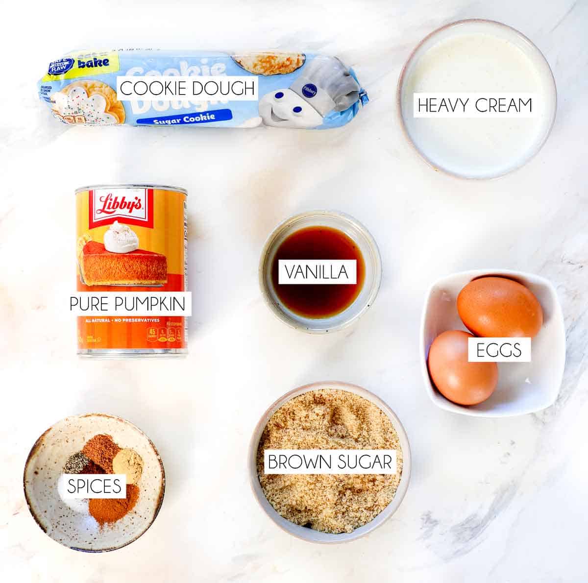 Top view of Mini Pumpkin Pie Ingredients: pure pumpkin, heavy cream, eggs, brown sugar, ground cinnamon, ground nutmeg, ground ginger, salt, cookie dough