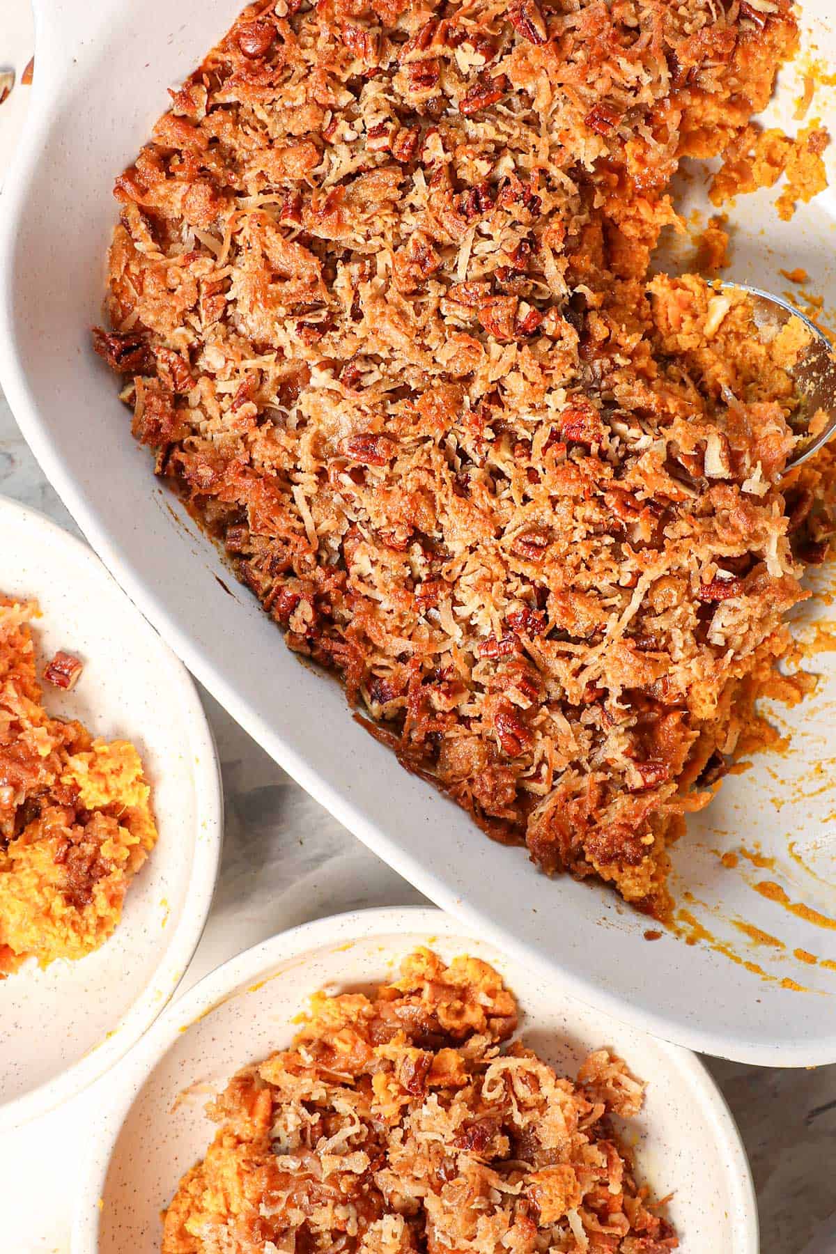 top view of Sweet Potato Casserole recipe by being served in a 9x13 dish with two serving bowls next to it