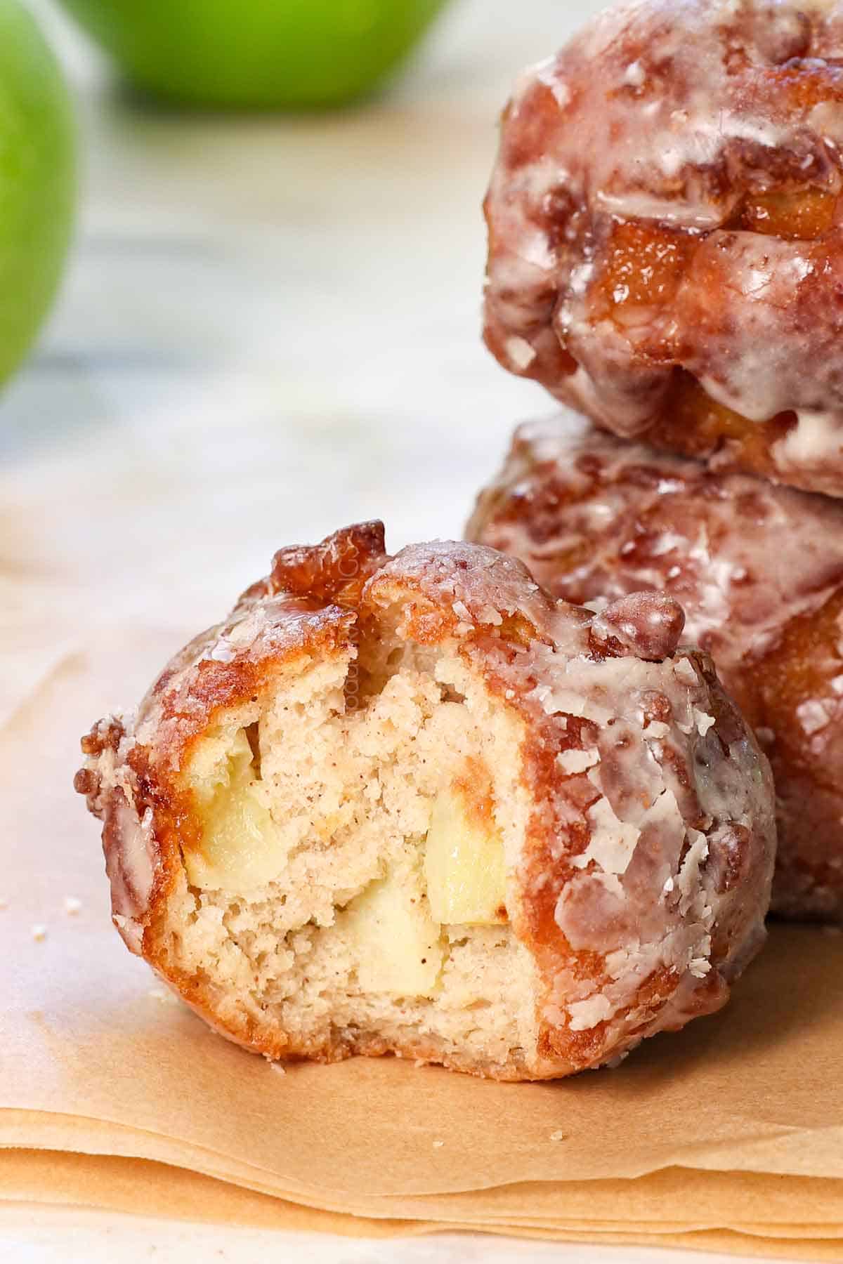 up close of homemade apple fritters with a bite take out showing how tender the inside is