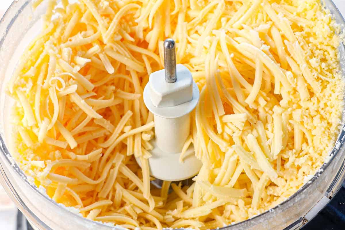 showing how to make fondue by grating the cheeses in a food processor