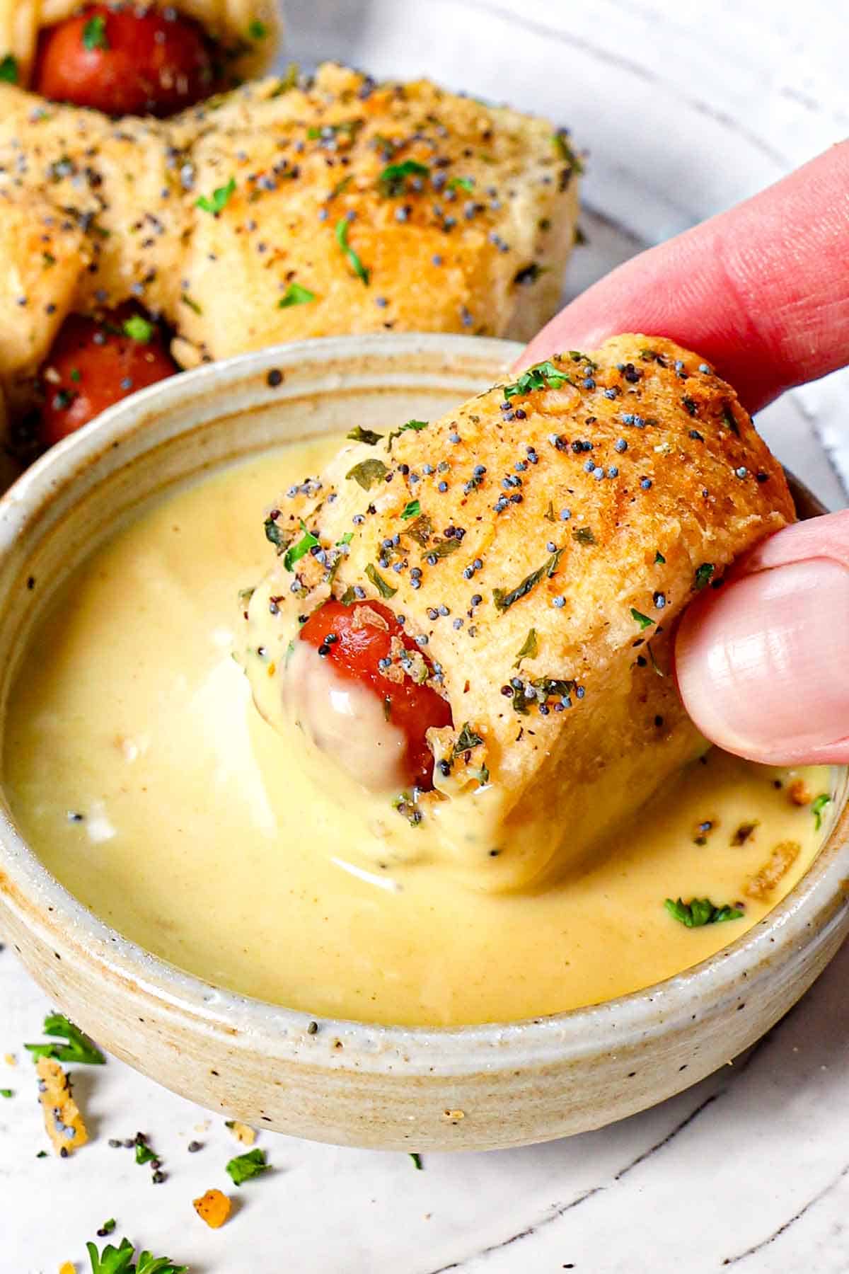 crescent pigs in a blanket being served on a plate and dipped in honey dijon mustard