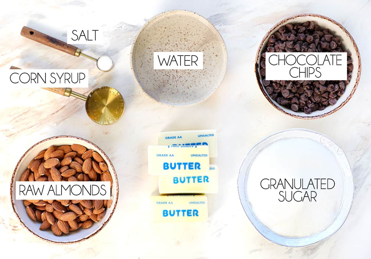 top view of almond roca ingredients: whole almonds, chocolate chips, butter, sugar, corn syrup, salt and water