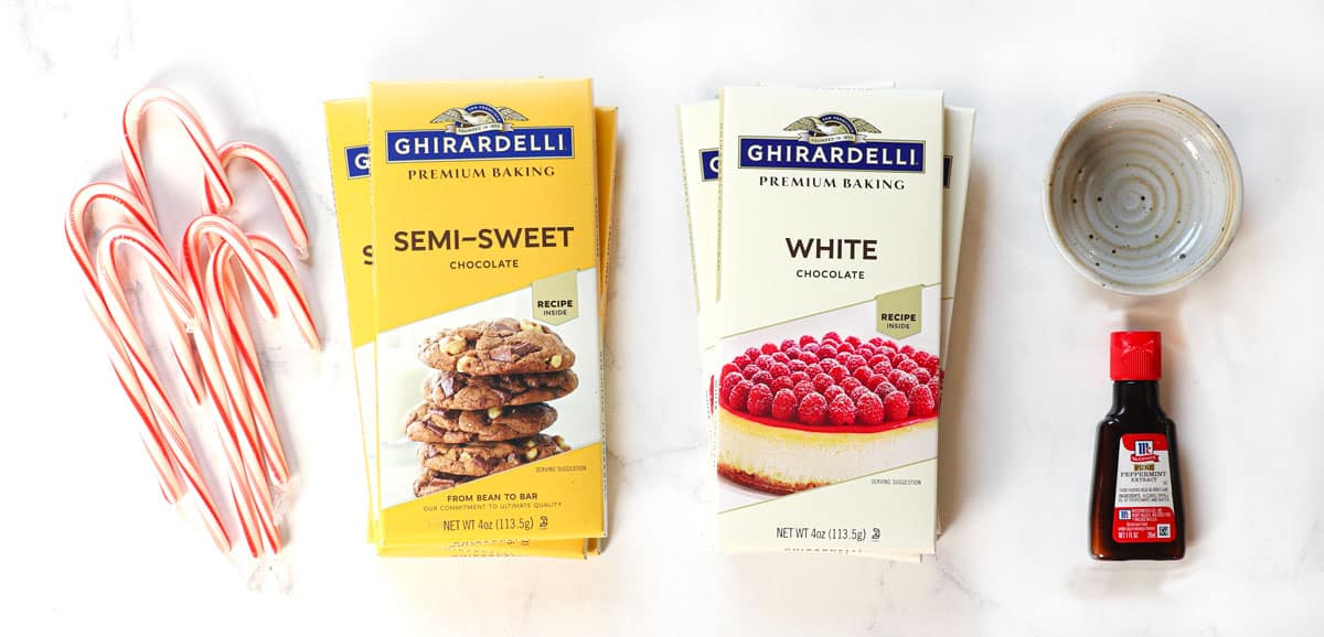 top view of peppermint bark ingredients: semi sweet baking chocolate, white baking chocolate, candy canes, peppermint extract, vegetable oil