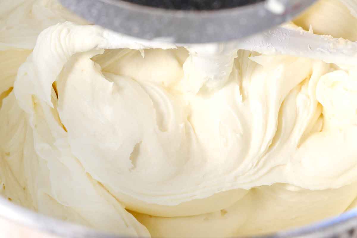 showing how to make red velvet cake with cream cheese frosting by whipping the ingredients together in a mixer