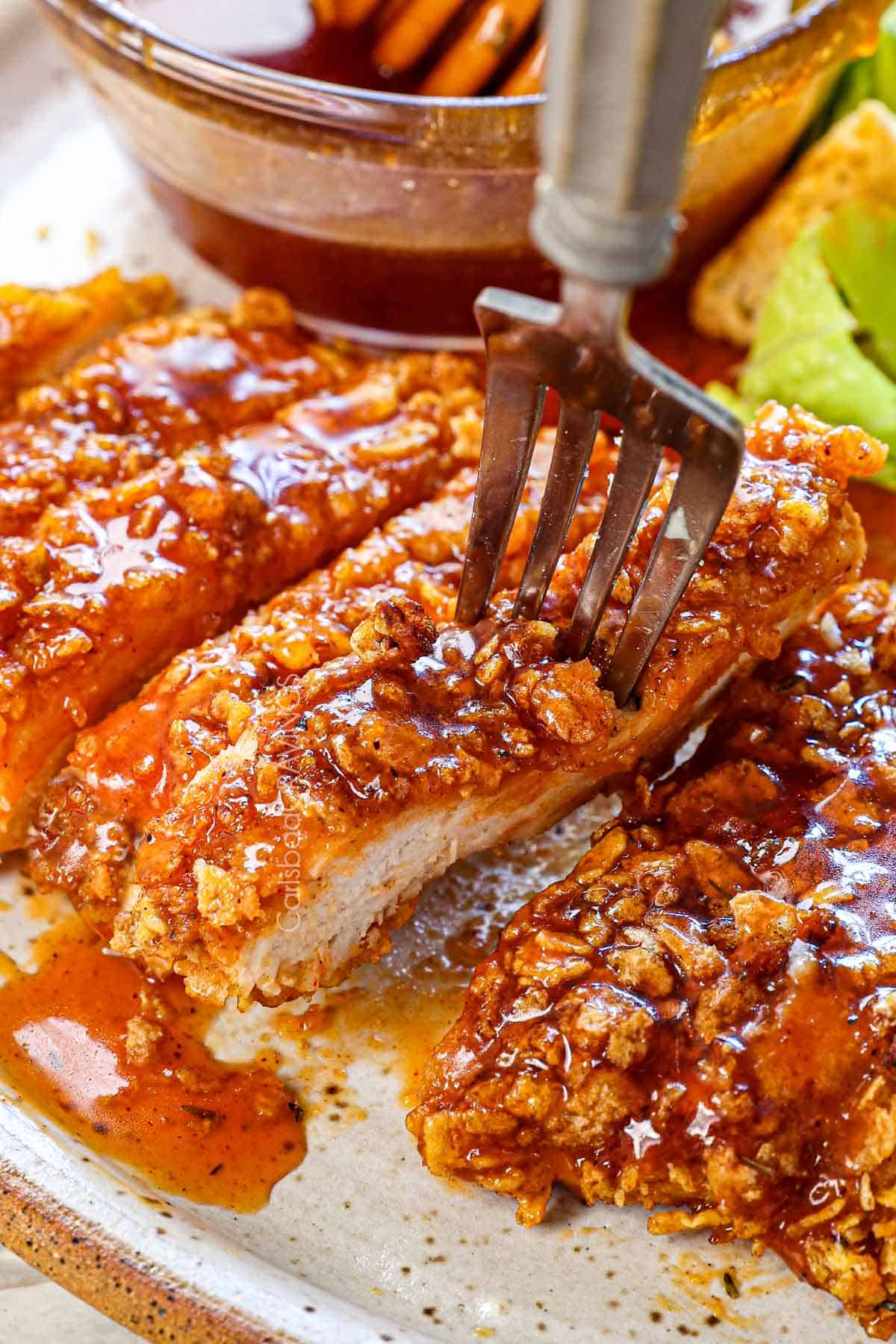 up close of a fork taking a bite of hot honey chicken showing how crispy, crunchy, and juicy it is