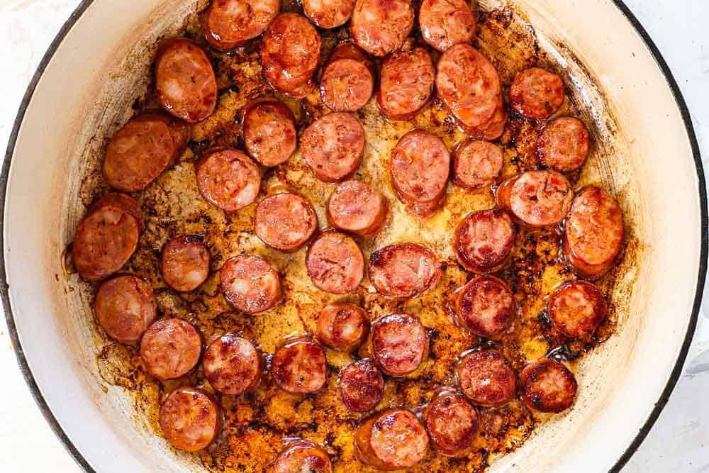 showing how to make jambalaya by browning the sausage in the pan