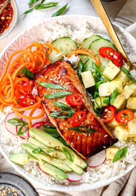 top view of miso glazed salmon being served over rice with vegetables, avocado, and green onions