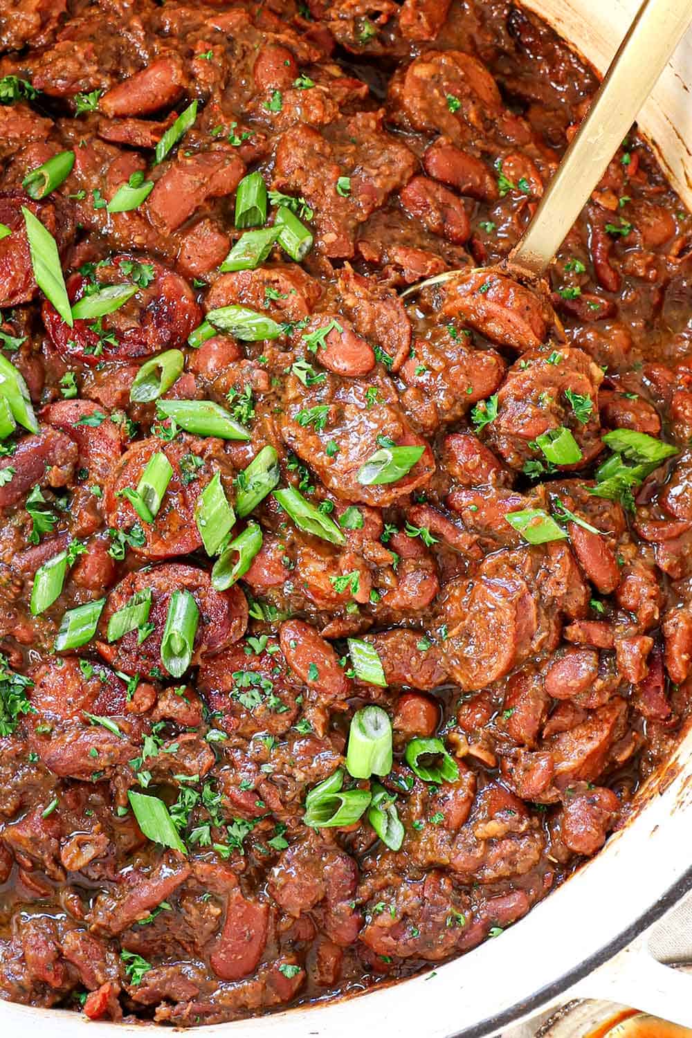 top view of red beans and rice recipe in a pot garnished with parsley and green onions showing its creamy consistincy