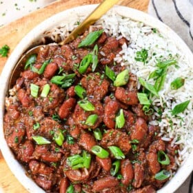 top view of red beans and rice being served in a bowl garnished with parsley and green onions