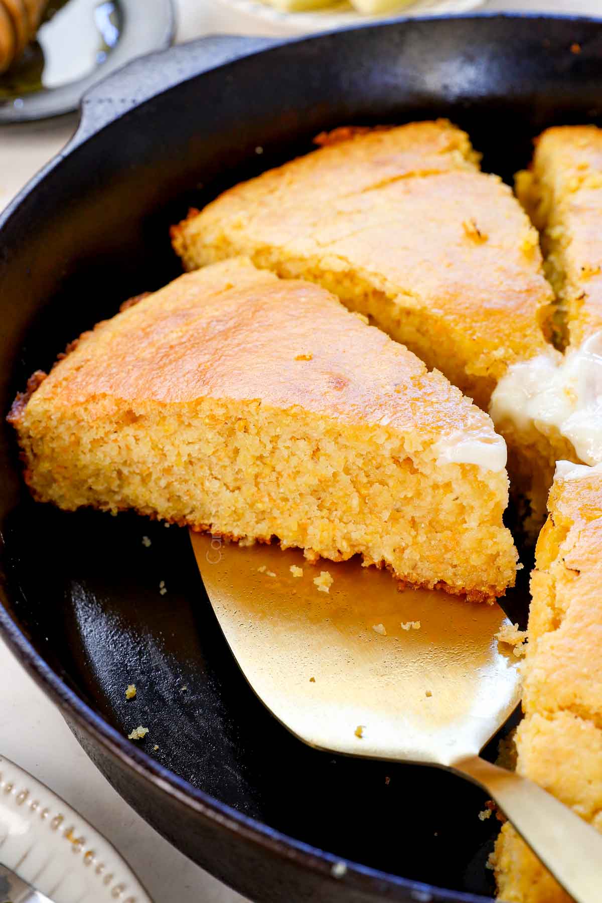 up close of a slice of cornbread in a cast iron skillet showing the tender crumb