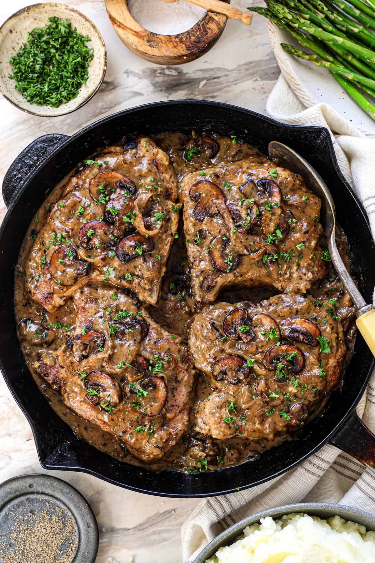showing how to make smothered pork chops by resting in the sauce