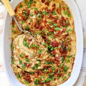 top view of holding mashed potato casserole recipe showing the panko topping, cheeses, bacon and, green onions