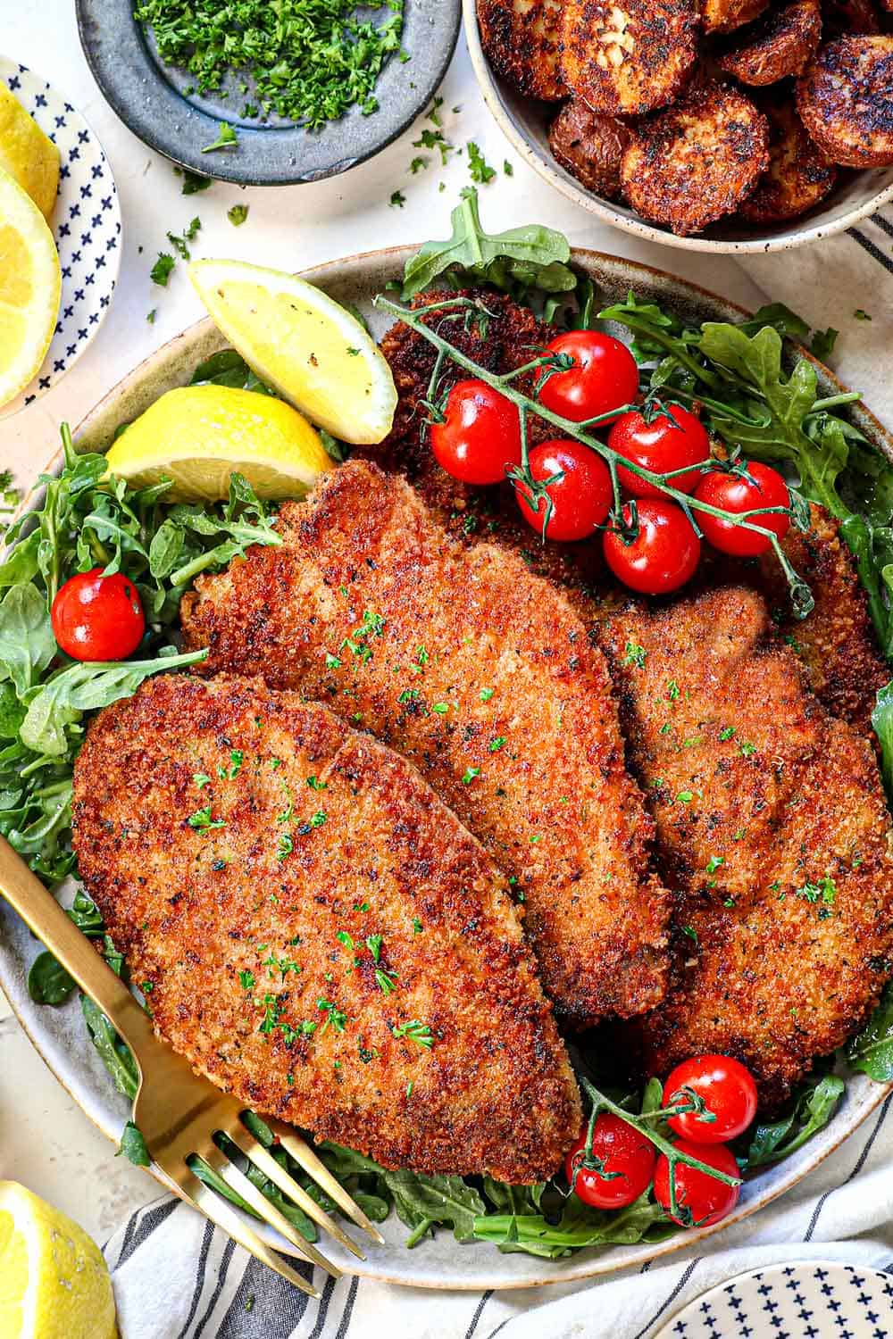 top view of chicken Milanese recipe being served over arugula with lemon wedges