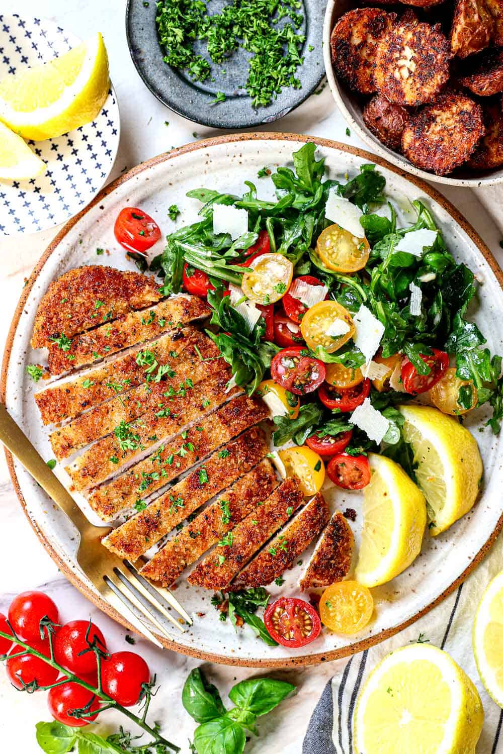 top view of Milanese chicken sliced on a plate with arugula salad