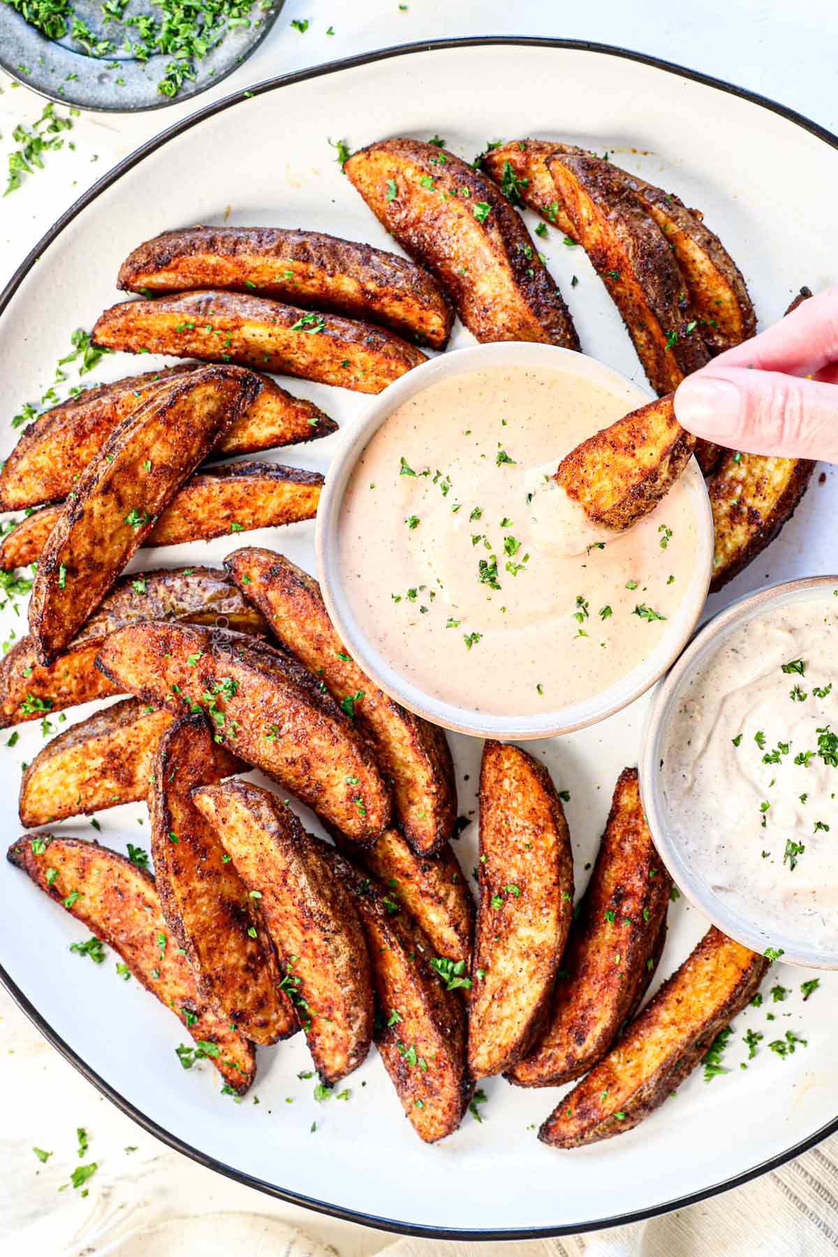 top view of dipping homemade potato wedges in fry sauce
