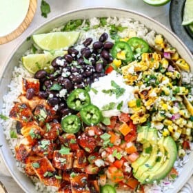 showing how to make chipotle honey chicken by adding the chicken to rice with beans, corn, pico e gallo, avocados, and cilantro