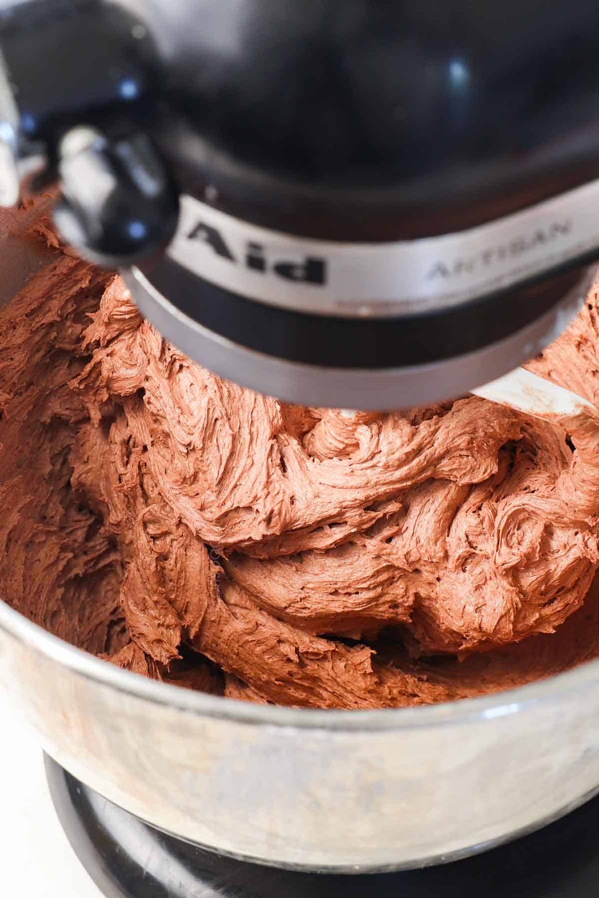 showing how to make chocolate frosting by whipping the frosting together until fluffy