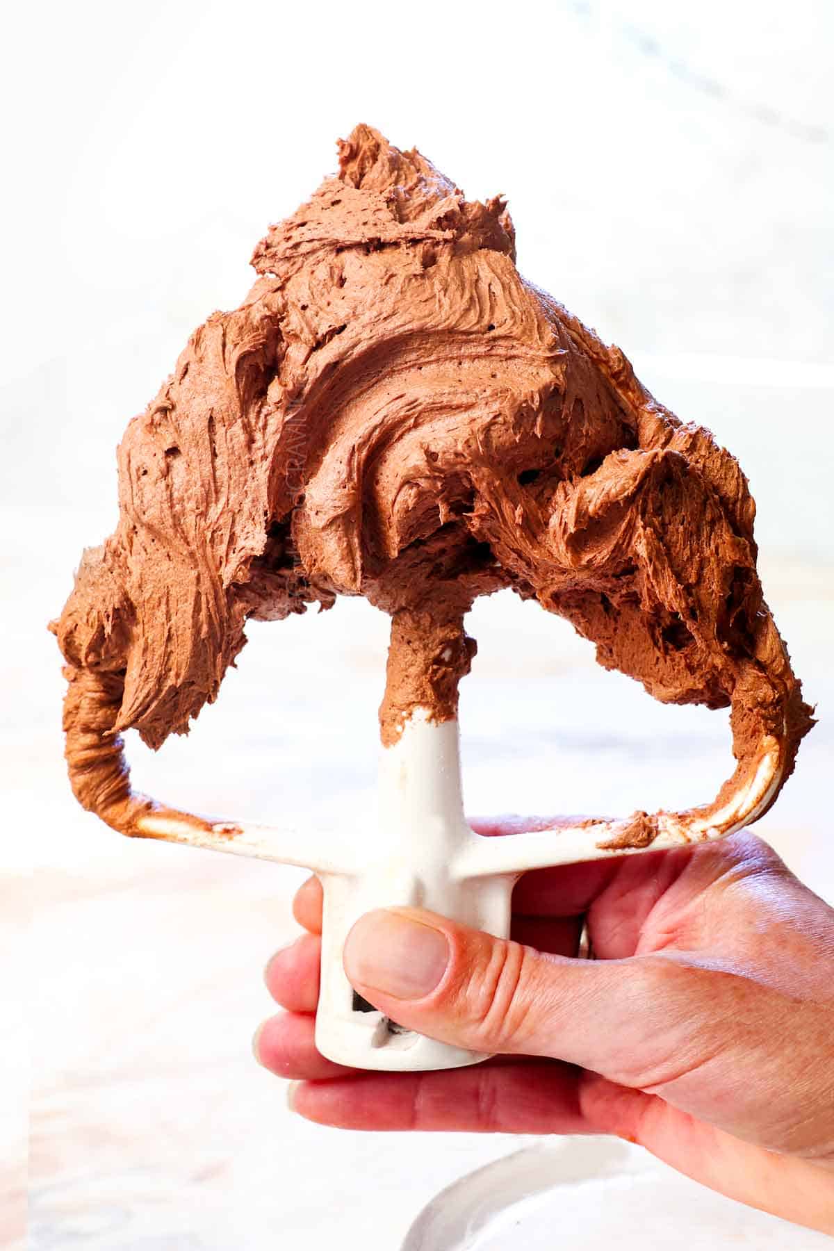 holding the mixer attachment with homemade chocolate frosting on it showing how thick and creamy it is