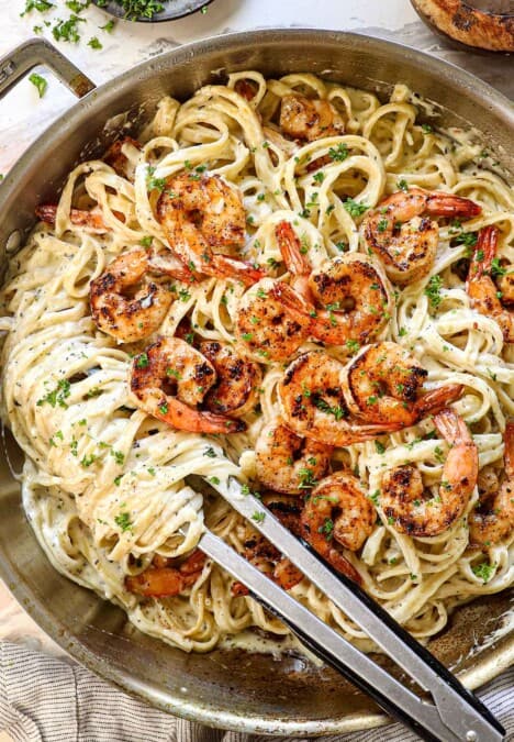 top view of shrimp alfredo with juicy seasoned shrimp on top of fettuccine