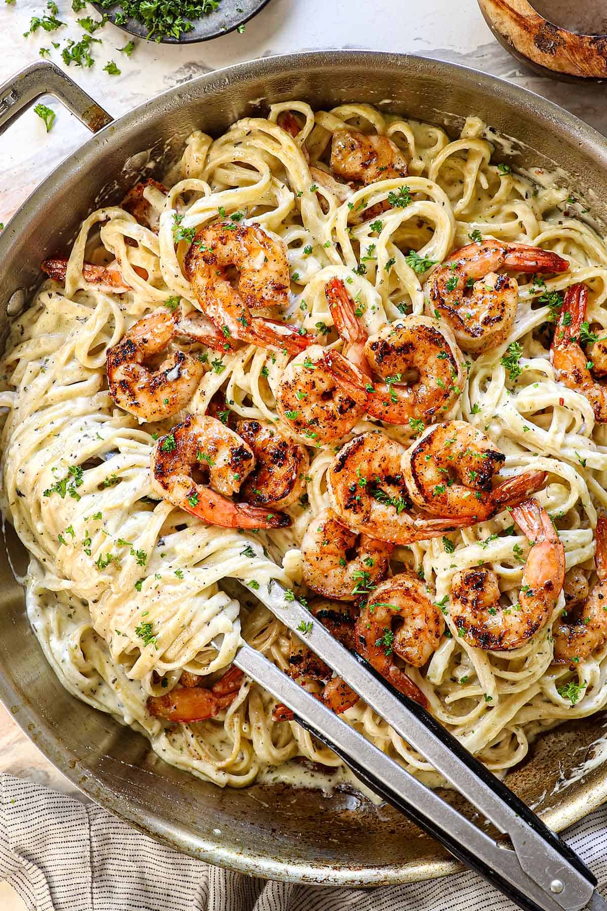 top view of shrimp alfredo with juicy seasoned shrimp on top of fettuccine