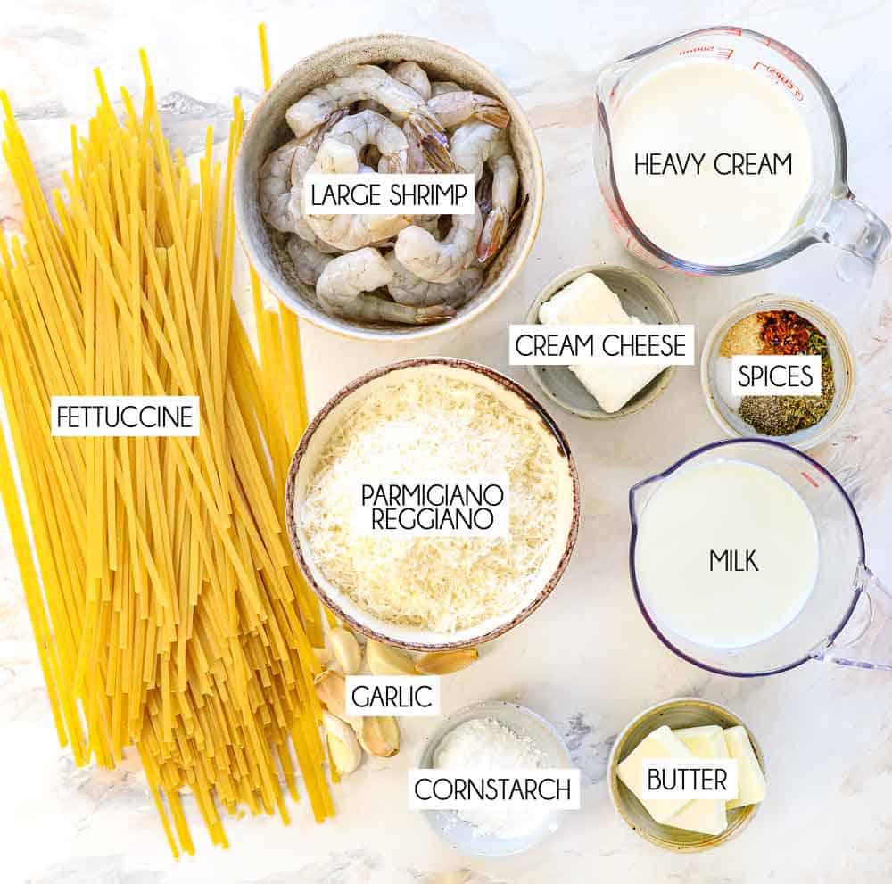 top view of shrimp alfredo ingredients: fettuccine, shrimp, heavy cream, milk, cream cheese, garlic, butter