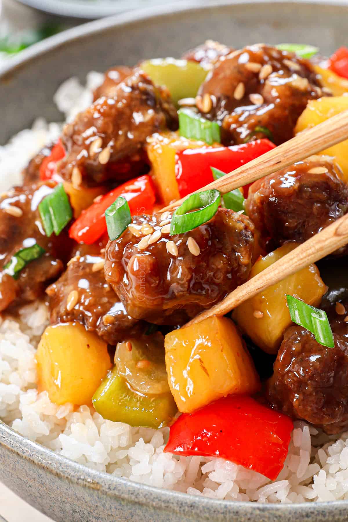 picking up a bite of sweet and sour pork with chopsticks showing how crispy it is