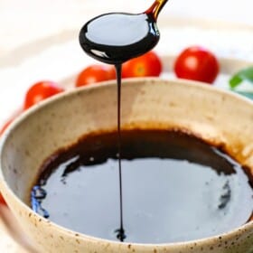 a spoon of balsamic vinegar glaze drizzling the glaze showing the consistency