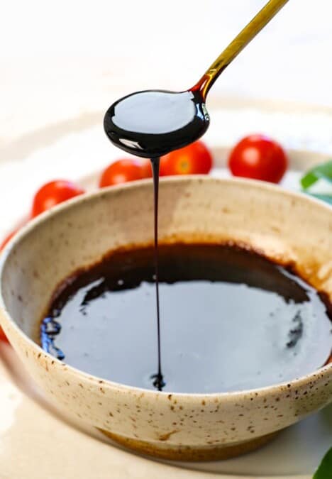 a spoon of balsamic vinegar glaze drizzling the glaze showing the consistency